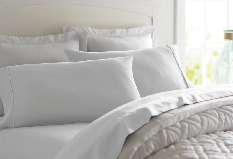 A bed with white sheets and pillow cases
