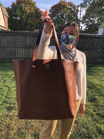 writer holding the bag closer, showing the gold monogrammed detail