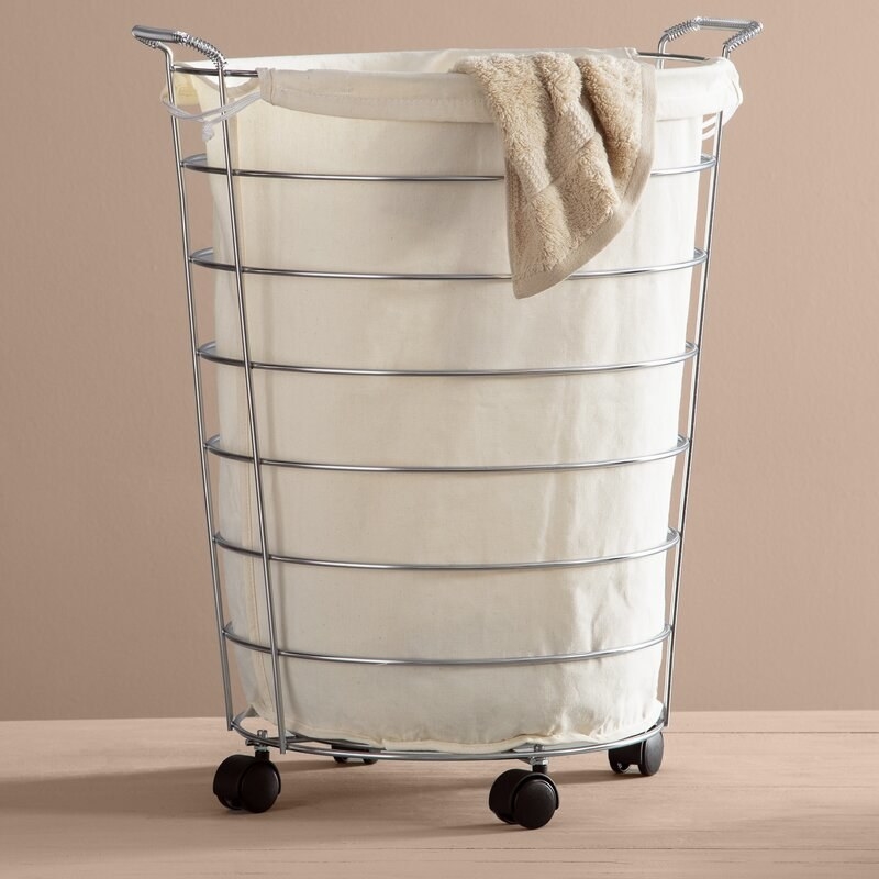 A white canvas hamper with wheels and metal frame
