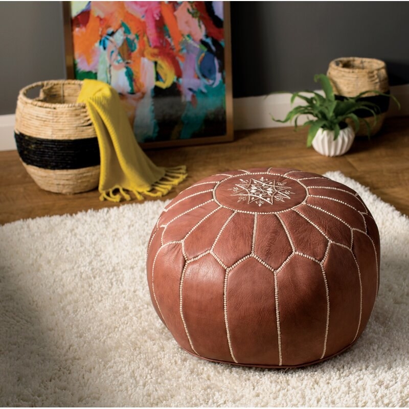 A brown leather foot stool on a white rug