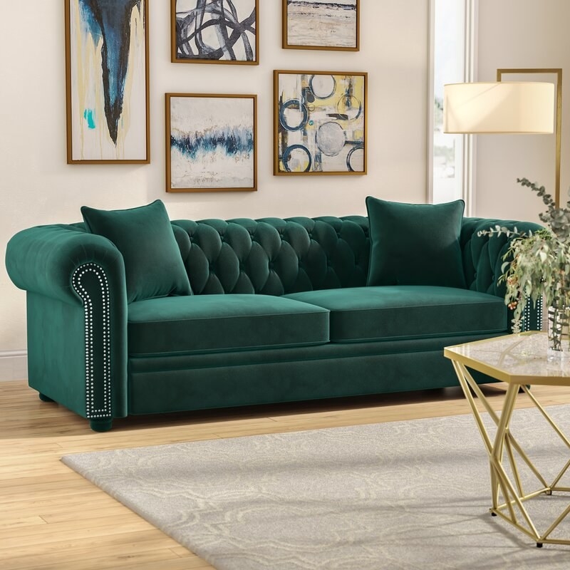 A green velvet couch in a living room 