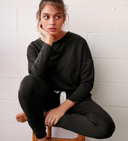 A model sitting on a stool while wearing the modal sweater