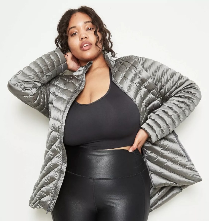 Model wearing silver puffer coat over black shirt and black pants