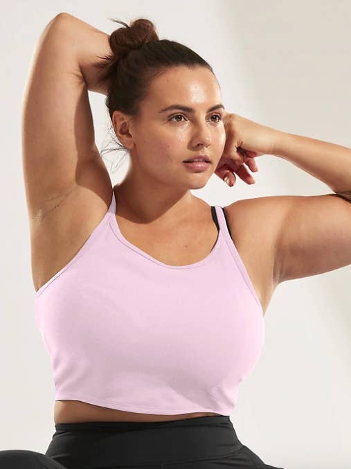 Model wears Athleta light pink twist back cami while practicing yoga