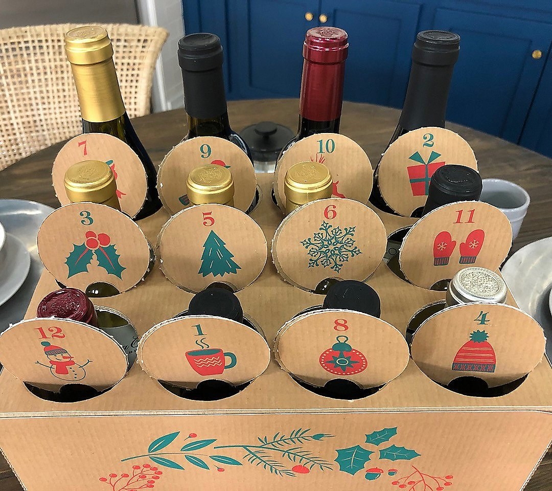 a cardboard carton with holes punched in the top for 12 days with a wine bottle in each one