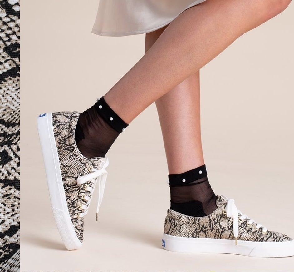 A person wearing the faux snakeskin Keds