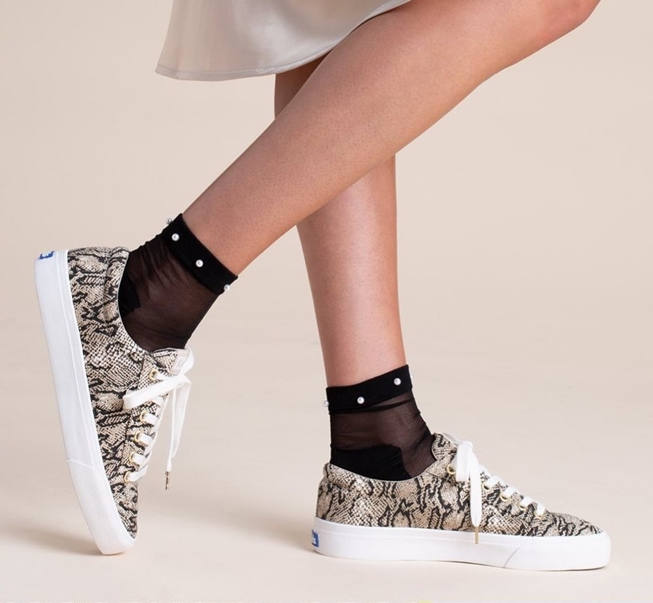 A person wearing the faux snakeskin Keds