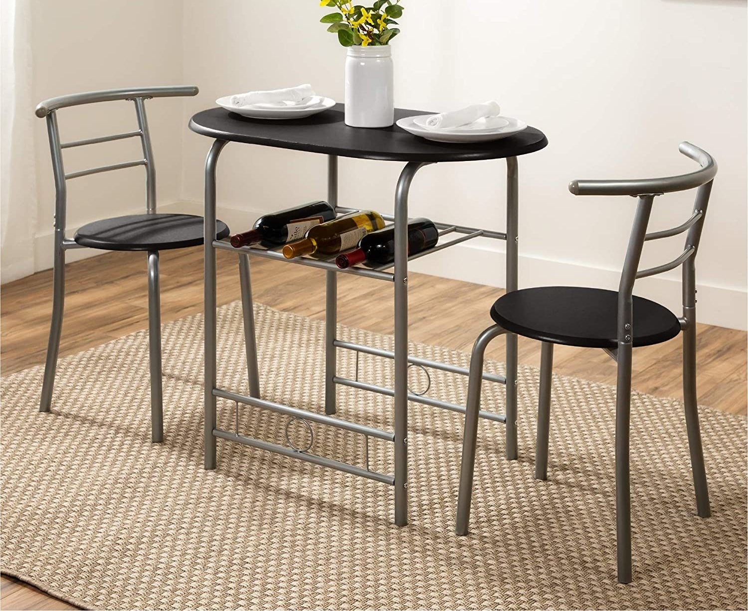A small oval table with a built-in rack underneath holding wine bottles and two small chairs