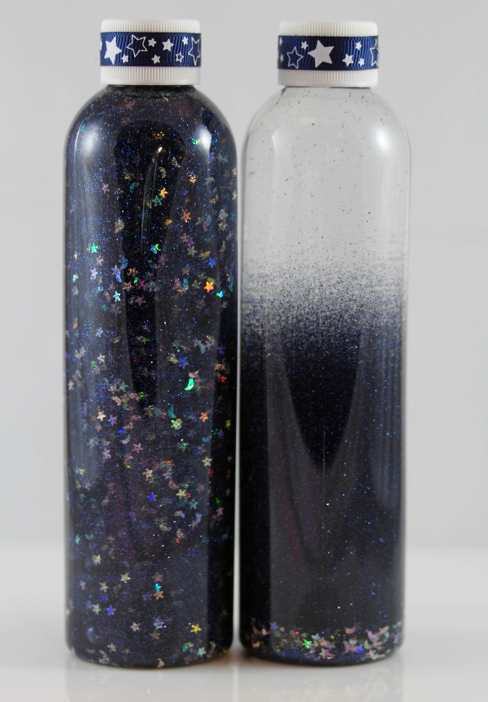 A water bottle full of black glass beads and glitter stars that fall to the bottom