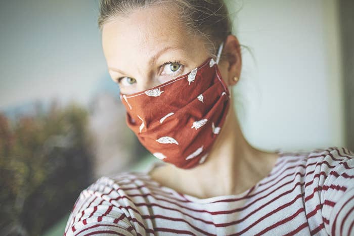 A person taking a selfie while wearing a cute printed mask