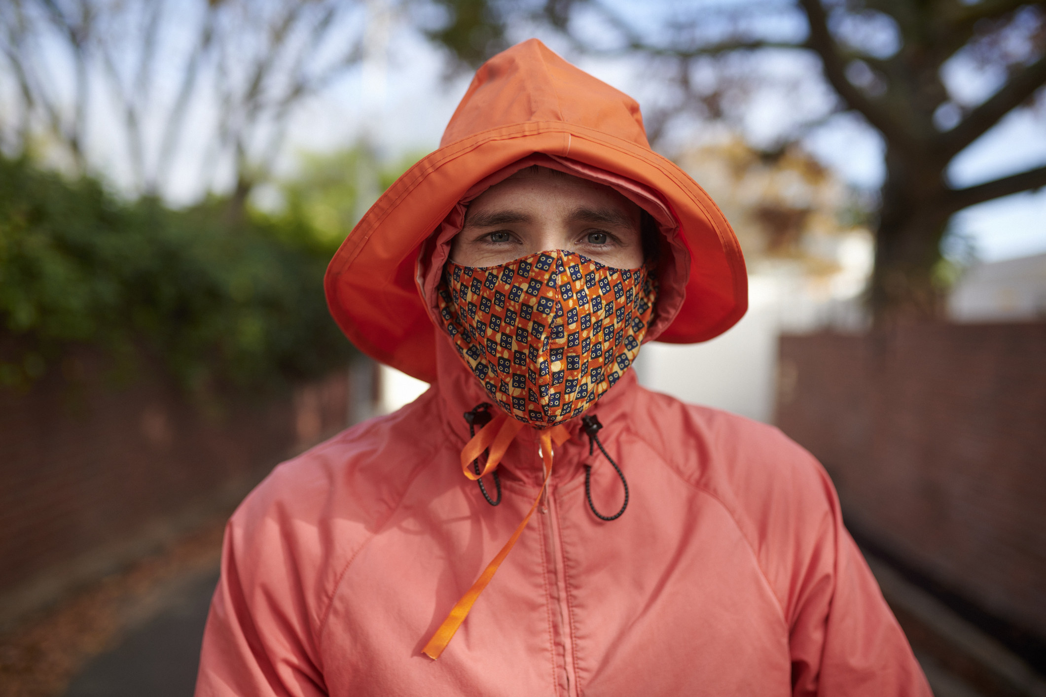 Une personne portant un imperméable et un chapeau avec un masque aux contours vifs.