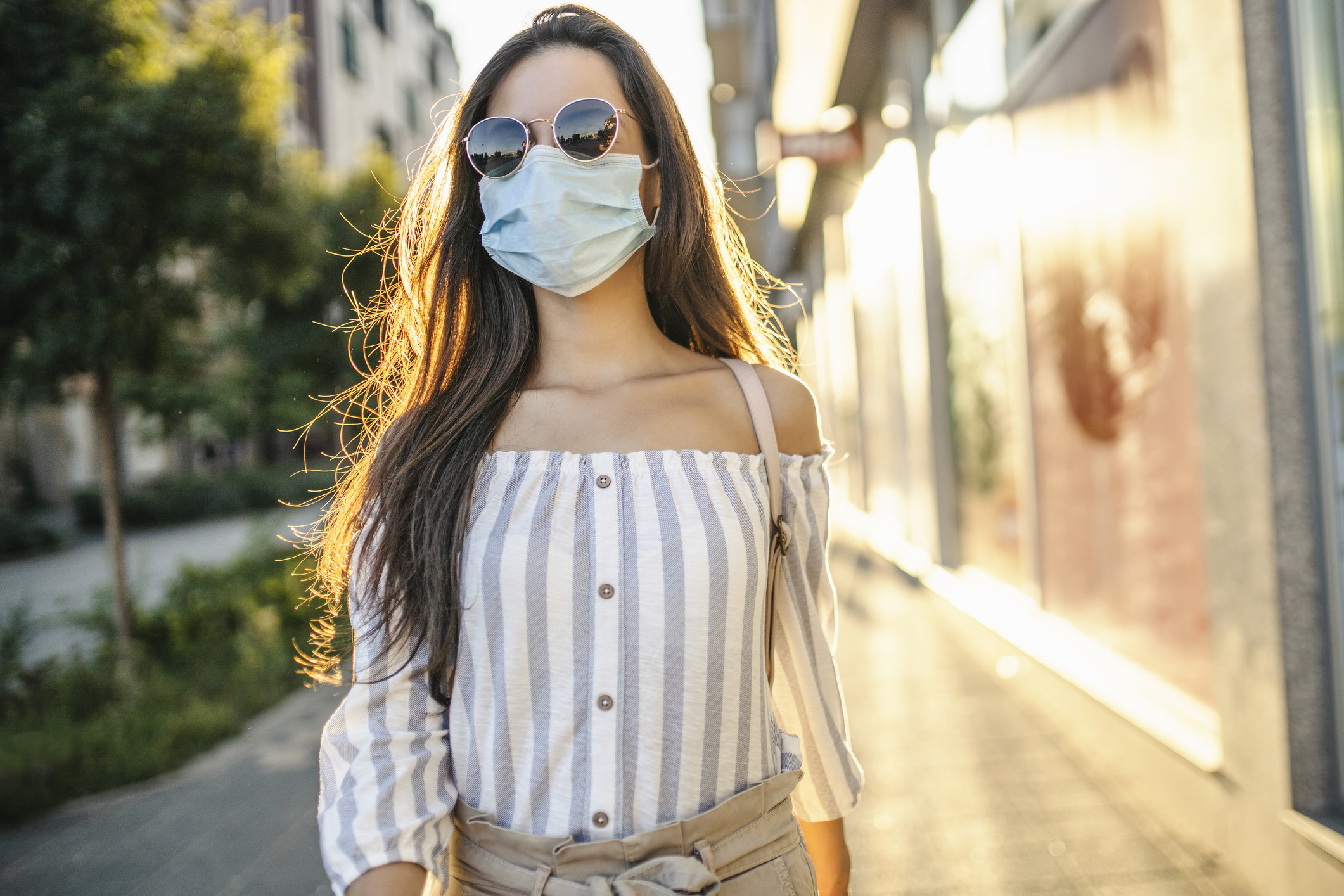 Une personne qui marche dans la rue en portant un masque jetable.