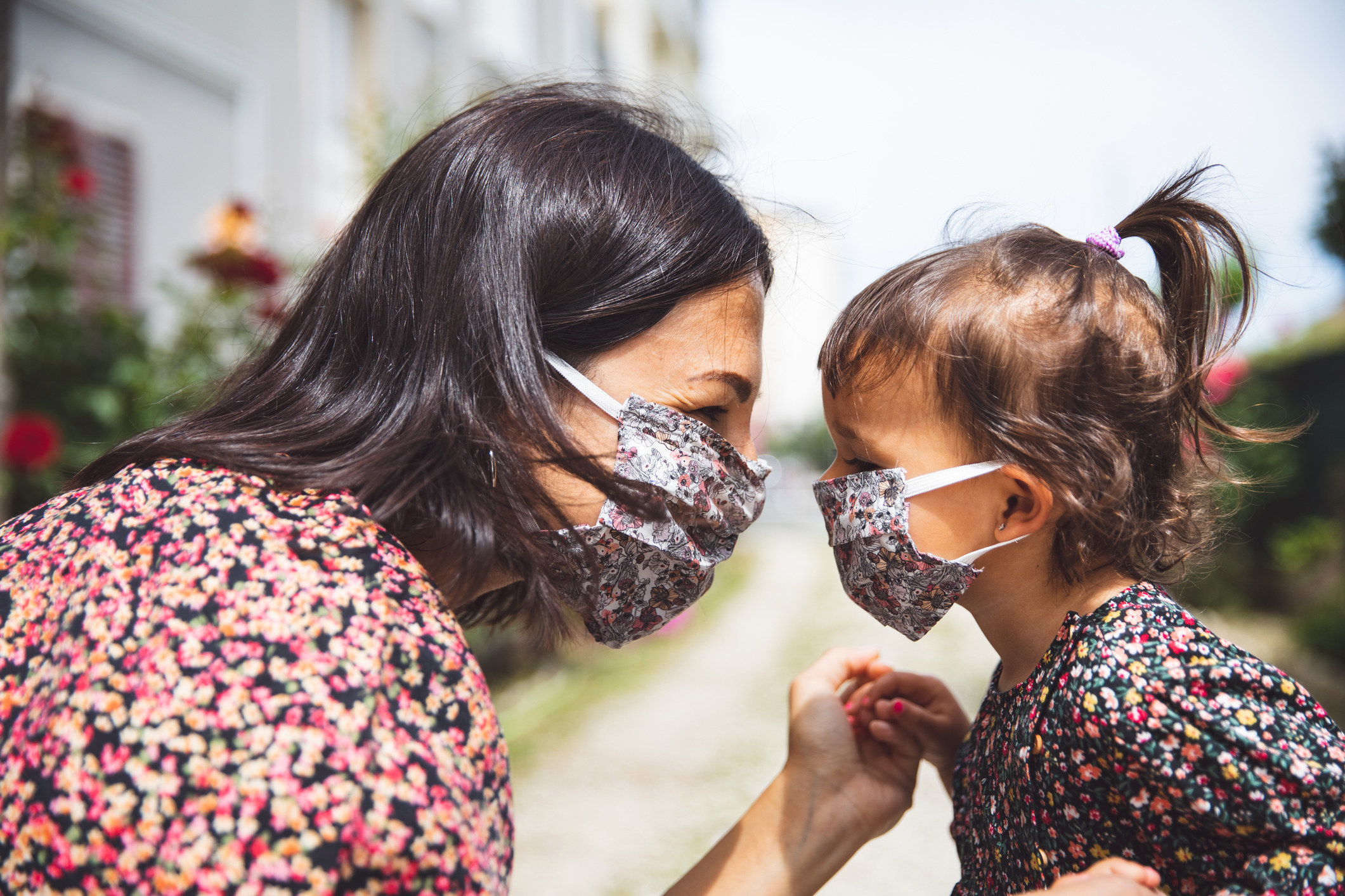 A woman and a toddler with their faces close together, wearing matching patterned masks.
