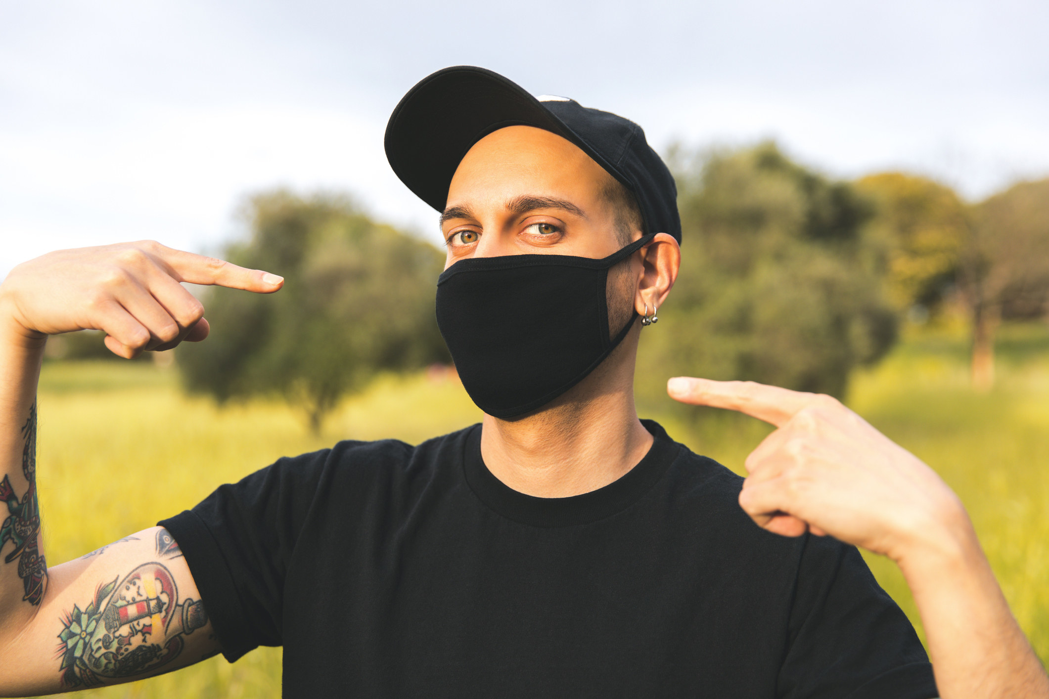 A person pointing to their mask while wearing an outfit all in one colour