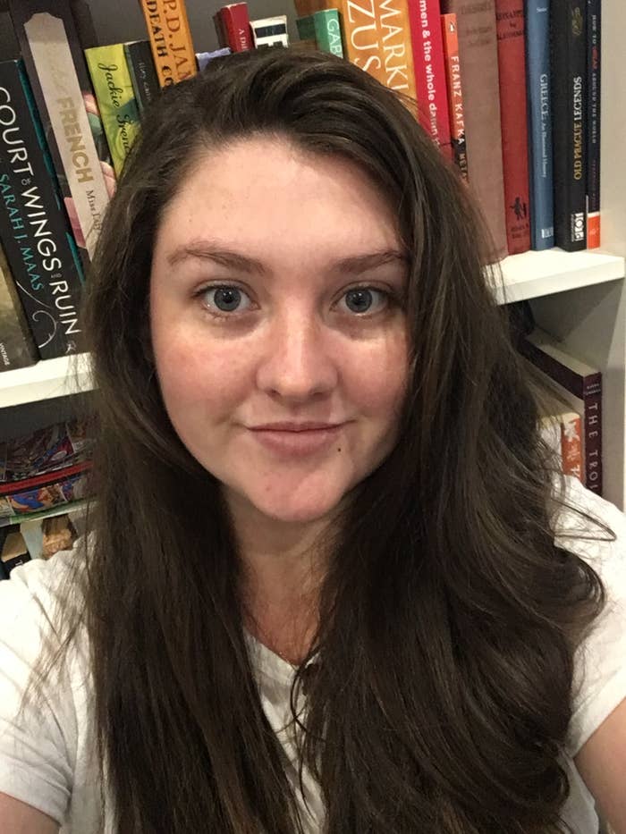 Woman with long dark hair and blue eyes taking selfies in front of a bookcase