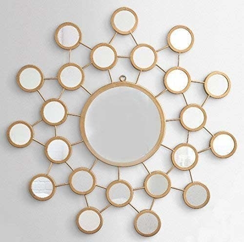 A wall mirror with a large golden-rimmed mirror in the centre and several smaller golden-rimmed mirrors protruding outwards, like the sun.