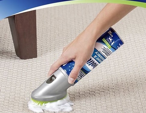 The cleaning foam, sprayed onto a rug and being scrubbed with the built-in scrubber on the top of the can