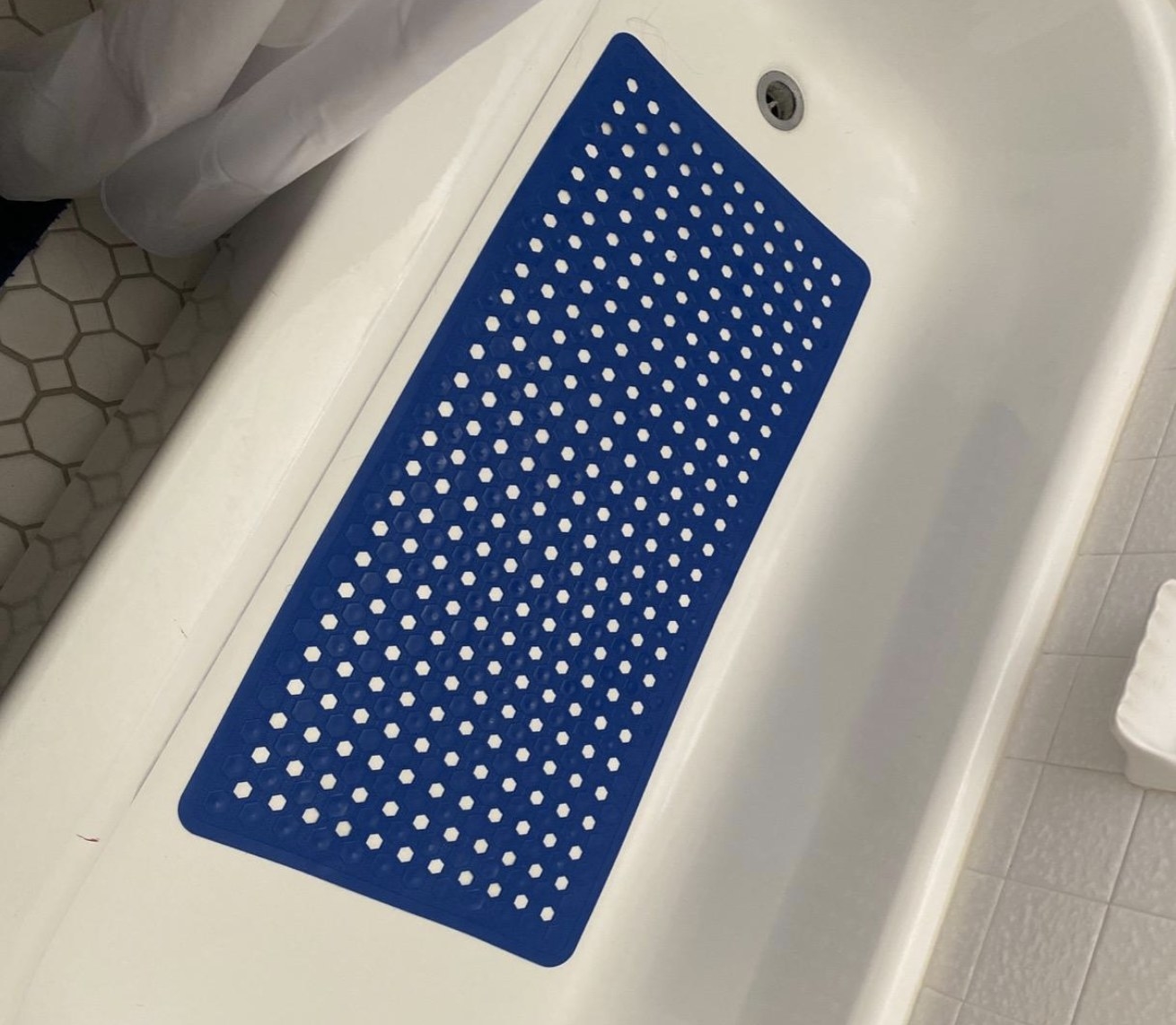 a royal blue bath mat at the bottom of a white tub