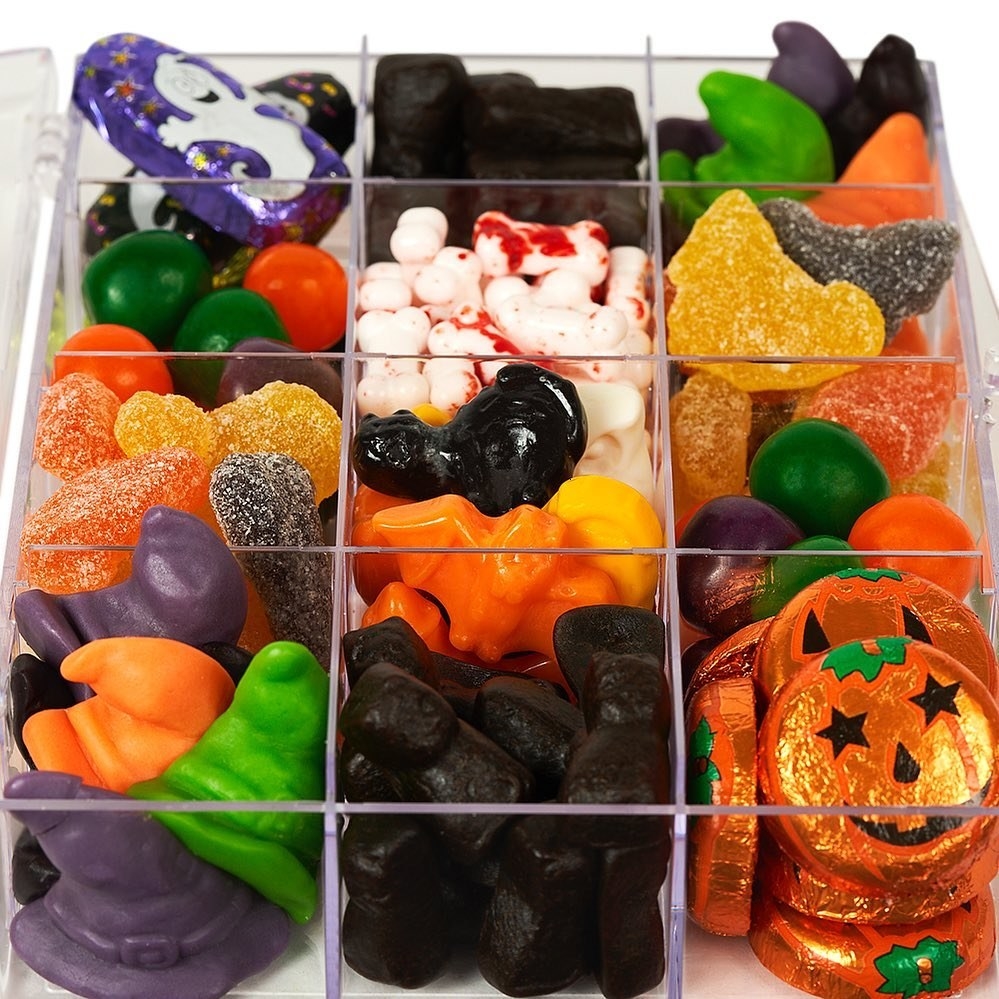 A clear tackle box with 12 squares full of different Halloween themed candies 