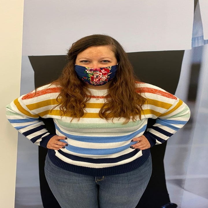 A reviewer wearing the crewneck sweater in white, orange, yellow, mint, blue, and navy stripes with jeans