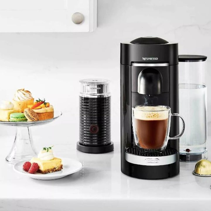 A glass cake stand next to a Nespresso coffee maker