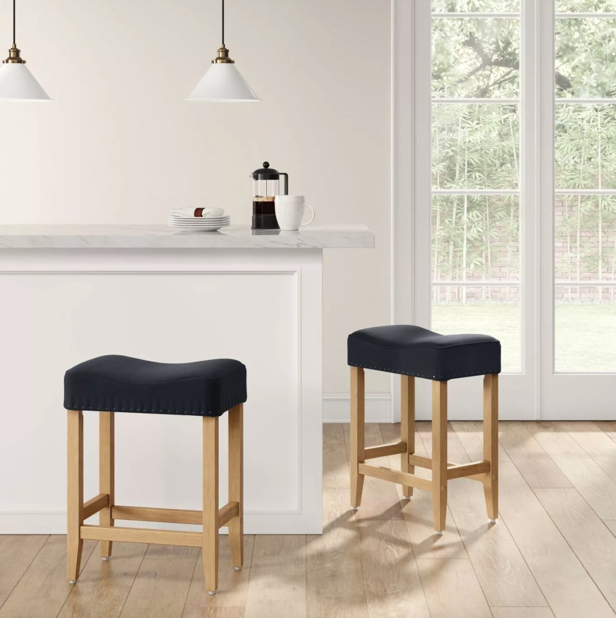 A pair of bar stools with navy cushions, nailhead detail, and wooden legs
