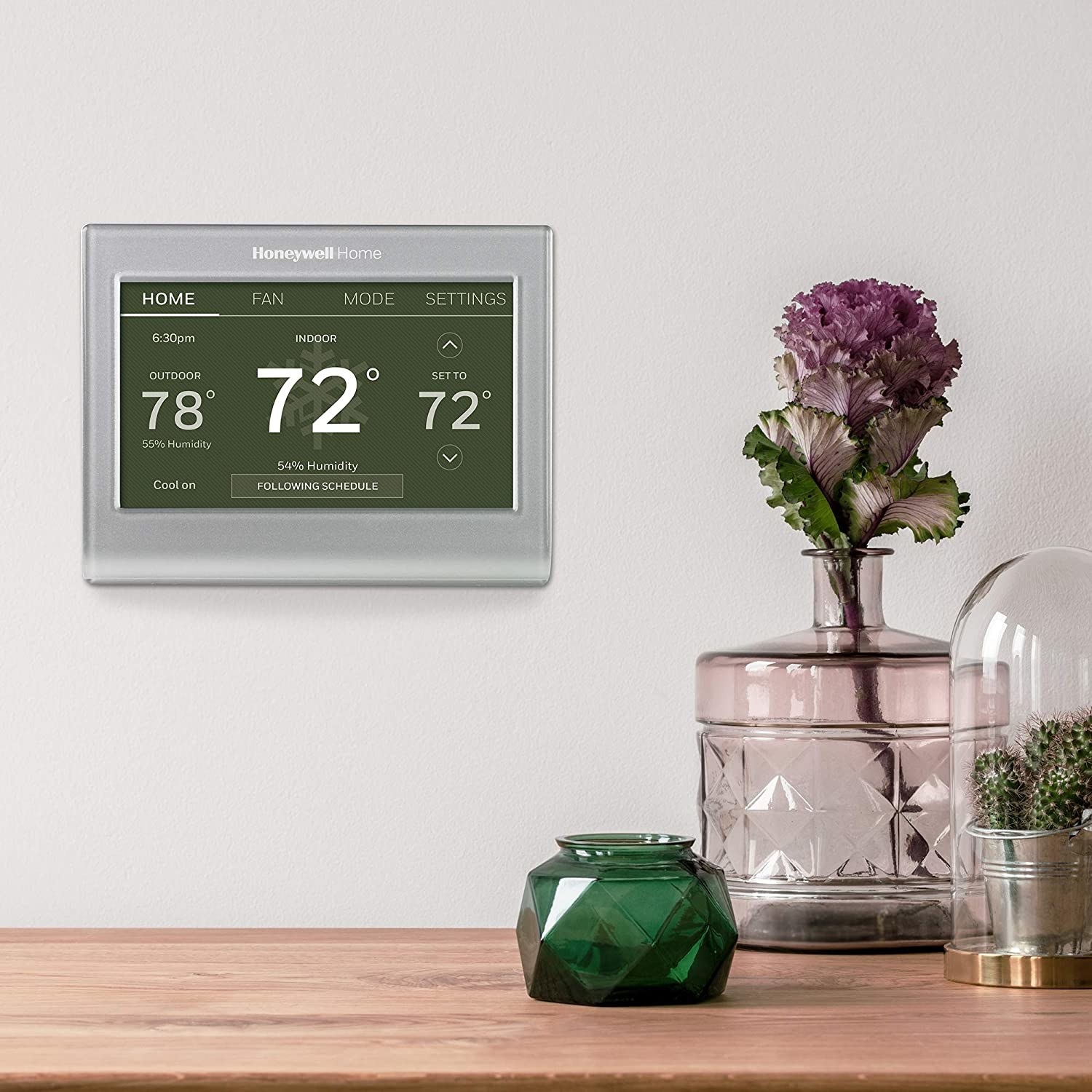 The thermostat hung on a wall next to some geometric glass vases