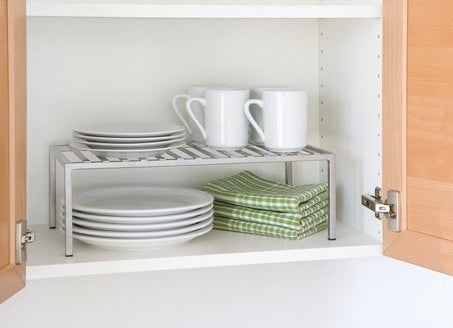 The rack, which has four legs, a slatted shelf, and rises about tall enough to hold a stack of four plates below it