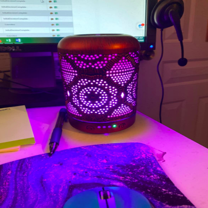 Reviewer uses copper engraved essential oil diffuser on their desk next to a computer monitor and swirly mouse pad