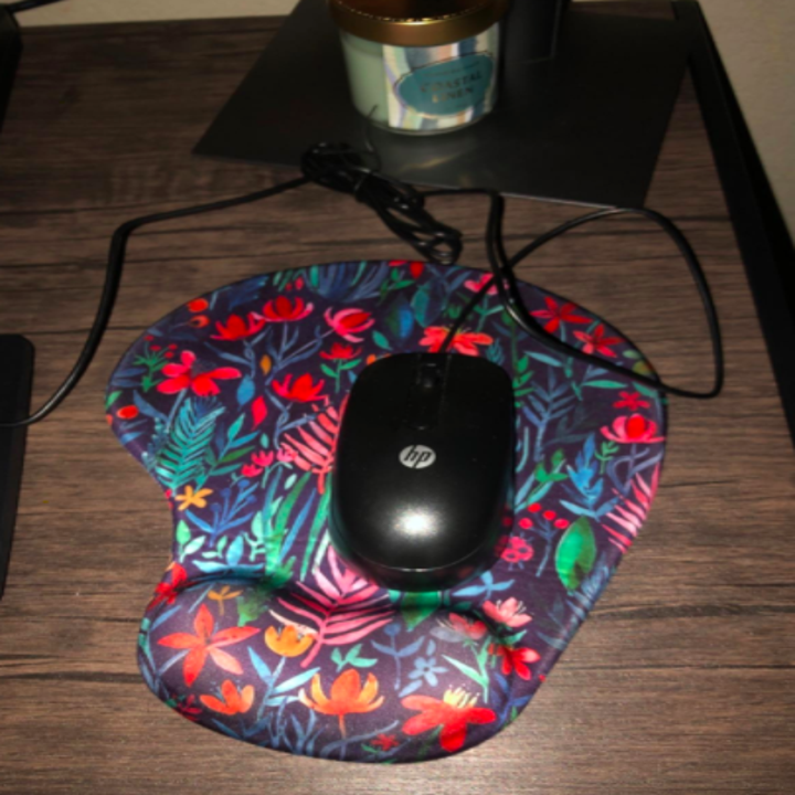 Reviewer shows same ergonomic mouse pad in a vibrant tropical flower pattern on their office desk