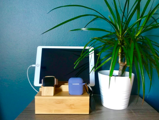 竹收取码头榨汁粉色和黑色smartwatch, AirPods,白色的平板电脑旁边白色的花瓶和植物在桌子上