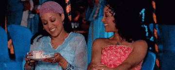 Tia and Tamera Mowry sit next to each other and smile as Alex and Cam in &quot;Twitches&quot;