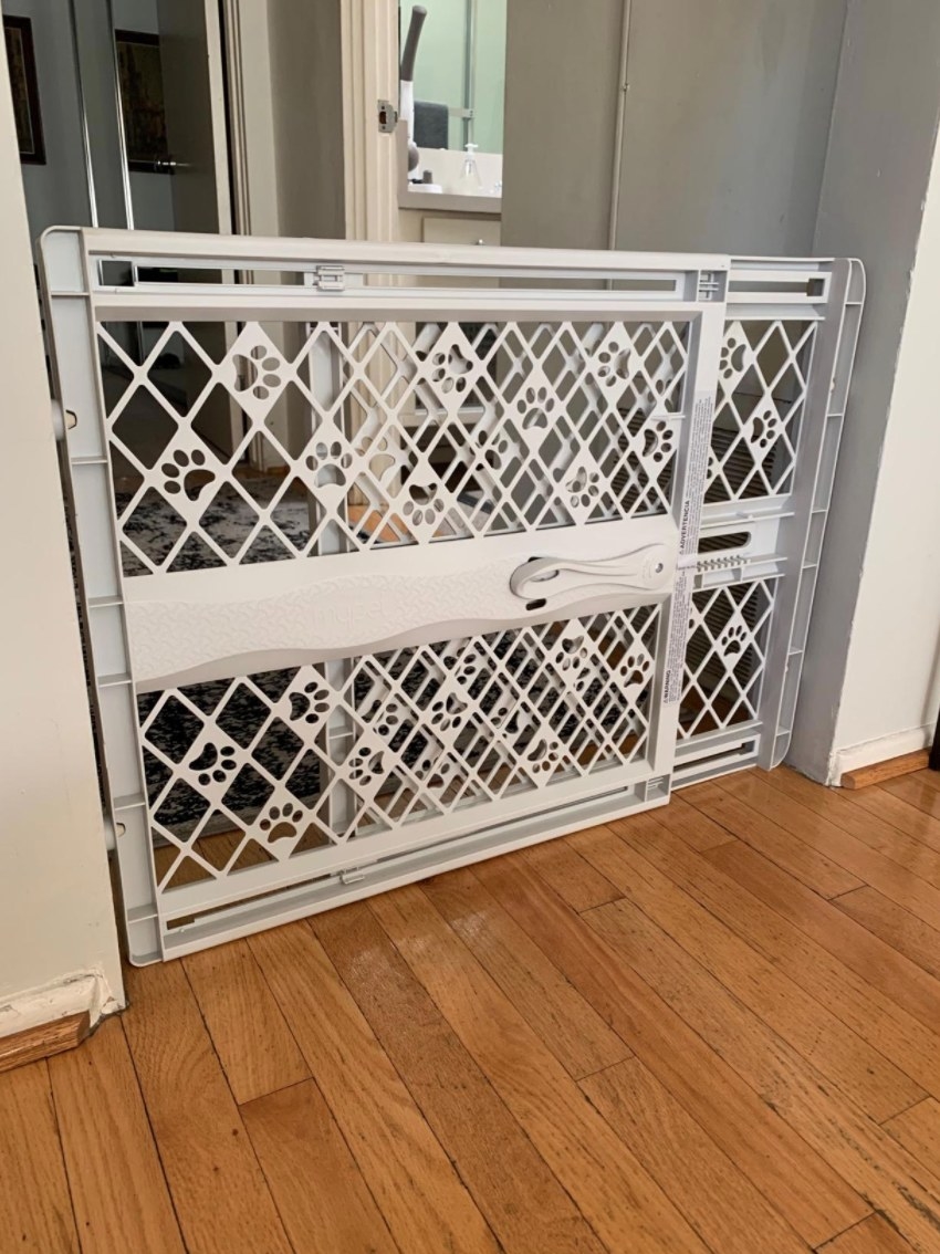 A reviewer&#x27;s white puppy gate being with the extendable feature being used