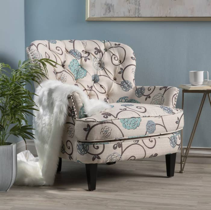 A floral accent chair with a blanket on top in a living room