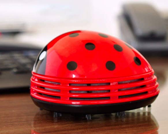 Red ladybug desk vacuum sucks up crumbs from a desktop