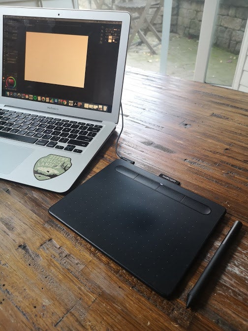The wacom drawing tablet and stylus plugged into a laptop 