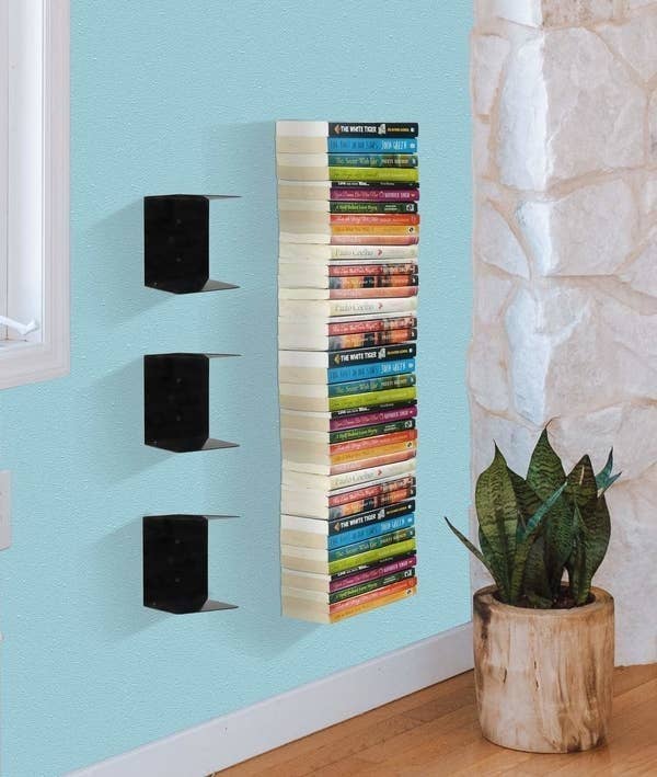 Three metal shelves with a top and bottom surface that appear to be invisible when stacked with books.