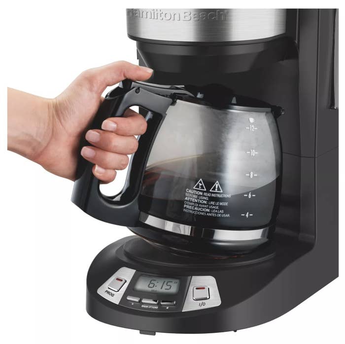 Person reaching for coffee in a coffee maker
