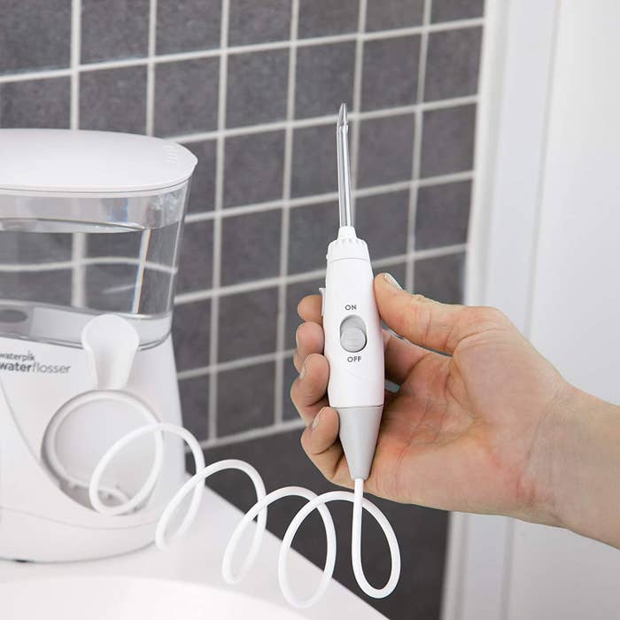 A person holding the flosser and showing the easy on-off switch