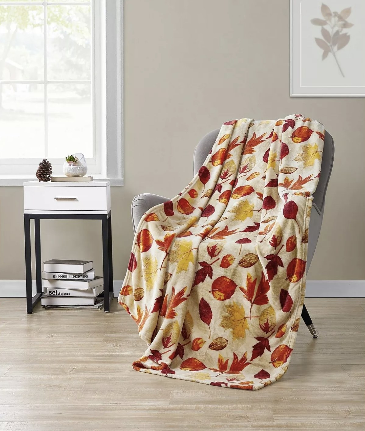 A throw blanket with autumn leaves on it on a chair in a living space