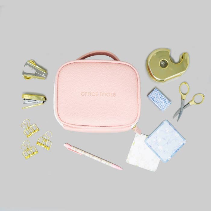 Office tool kit set with golden tools, a pink bag, pink mechanical pencil, and white and blue note pads