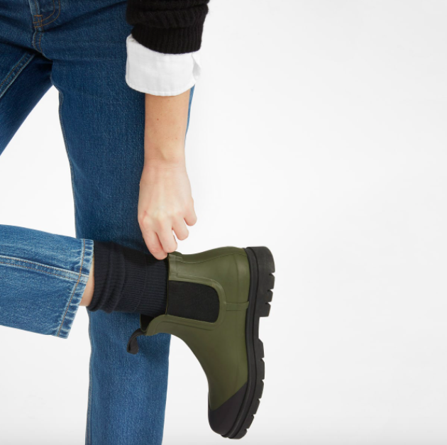 person pulling on ankle length rain boots