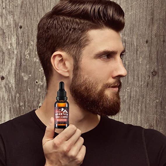 A person golds a beard oil and shows their beard