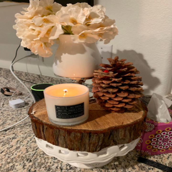 Reviewer sets white candle on a wooden stand on their marble covered desk