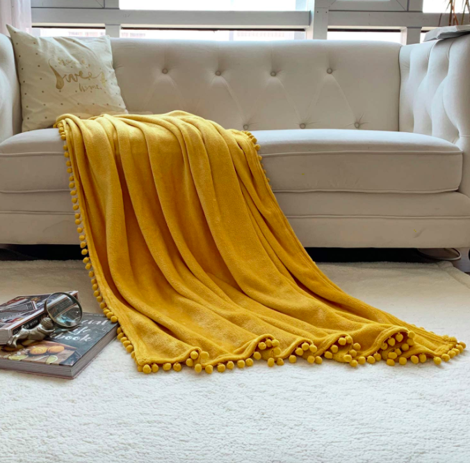 芥末黄毯子和机关炮边缘上的一个白色的沙发上