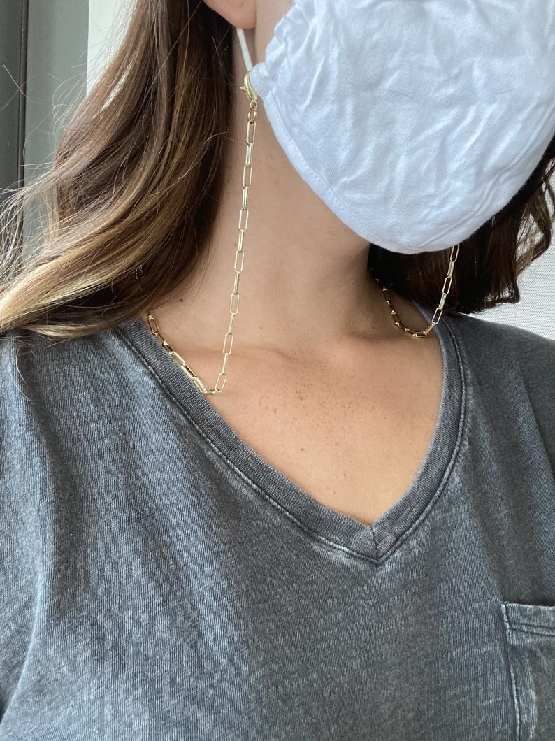 Model wearing a mask with the golden chain