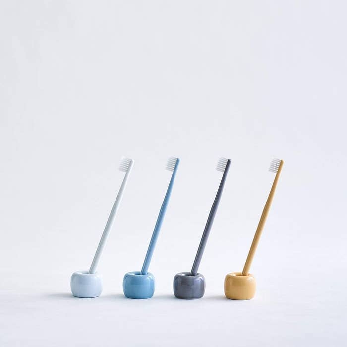 Four toothbrush holders of different colors holding a matching toothbrush