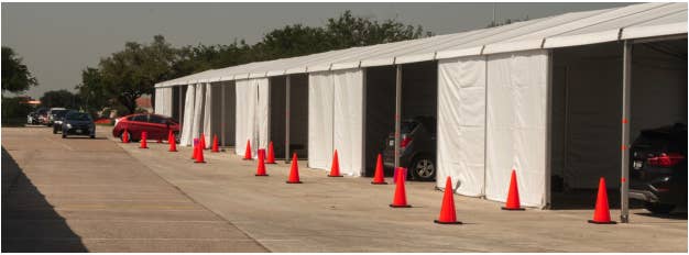 Drive-thru voting site in Harris County featuring a white tent structure with orange cones out front and cars inside