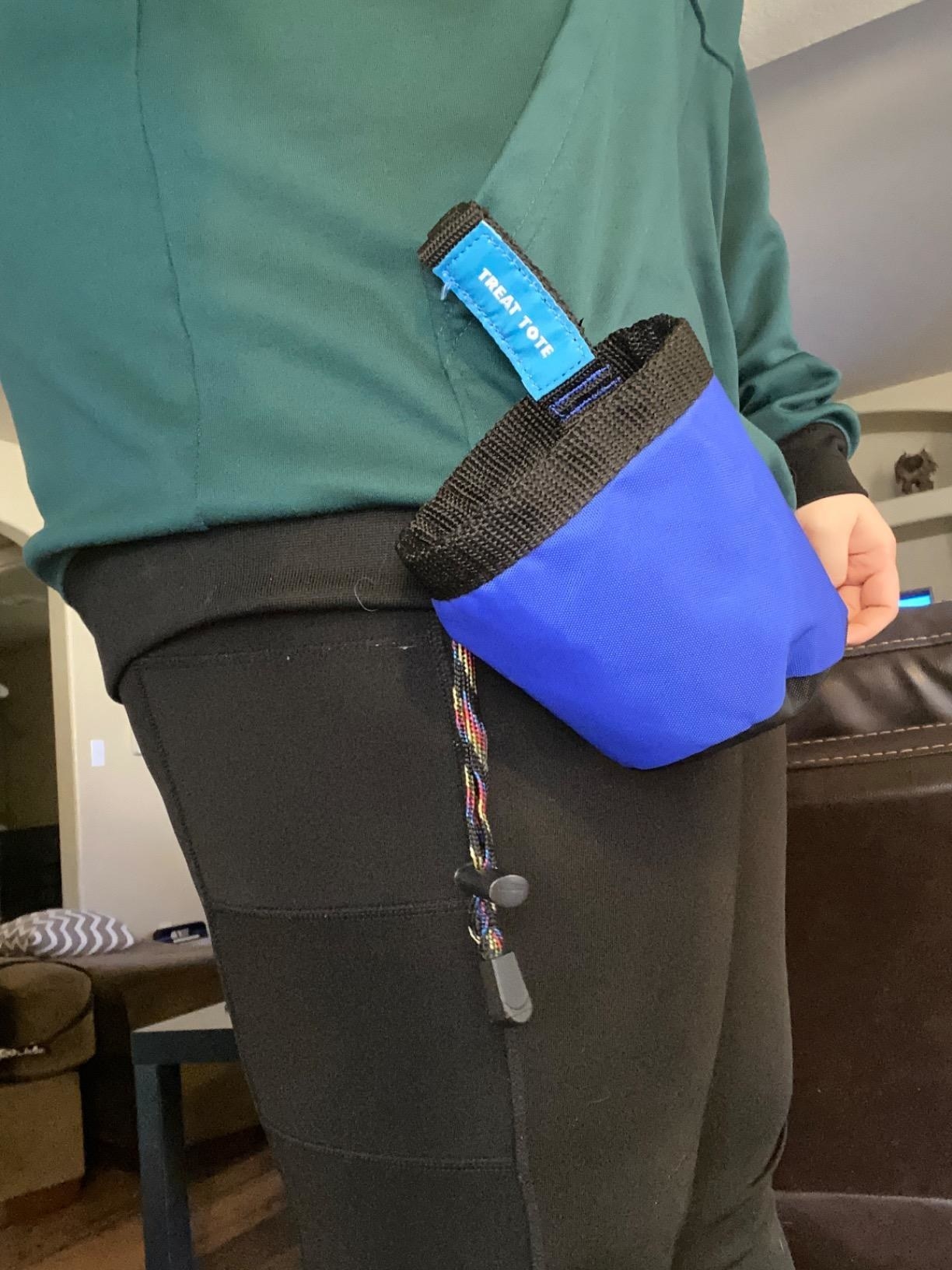 A reviewer wearing the treat tote clipped to the waistband of their pants