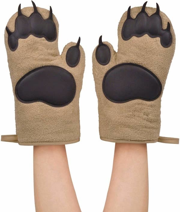 a model wearing two oven mitts that look like bear paws